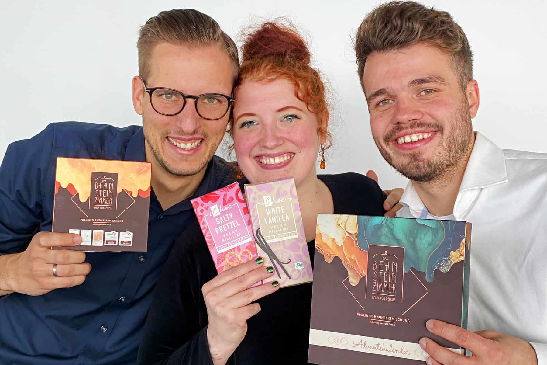 Gerrit Wiezoreck, Solvejg Klein & Noel Meyer von Ecofinia und Das Bernsteinzimmer nebeneinander, halten Schokoladenprodukte in den Händen
