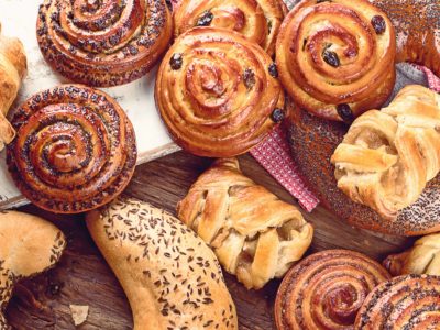 StockBreads, buns, croissants. Bakery ingredients on wooden background. Breakfast food concept. Top view