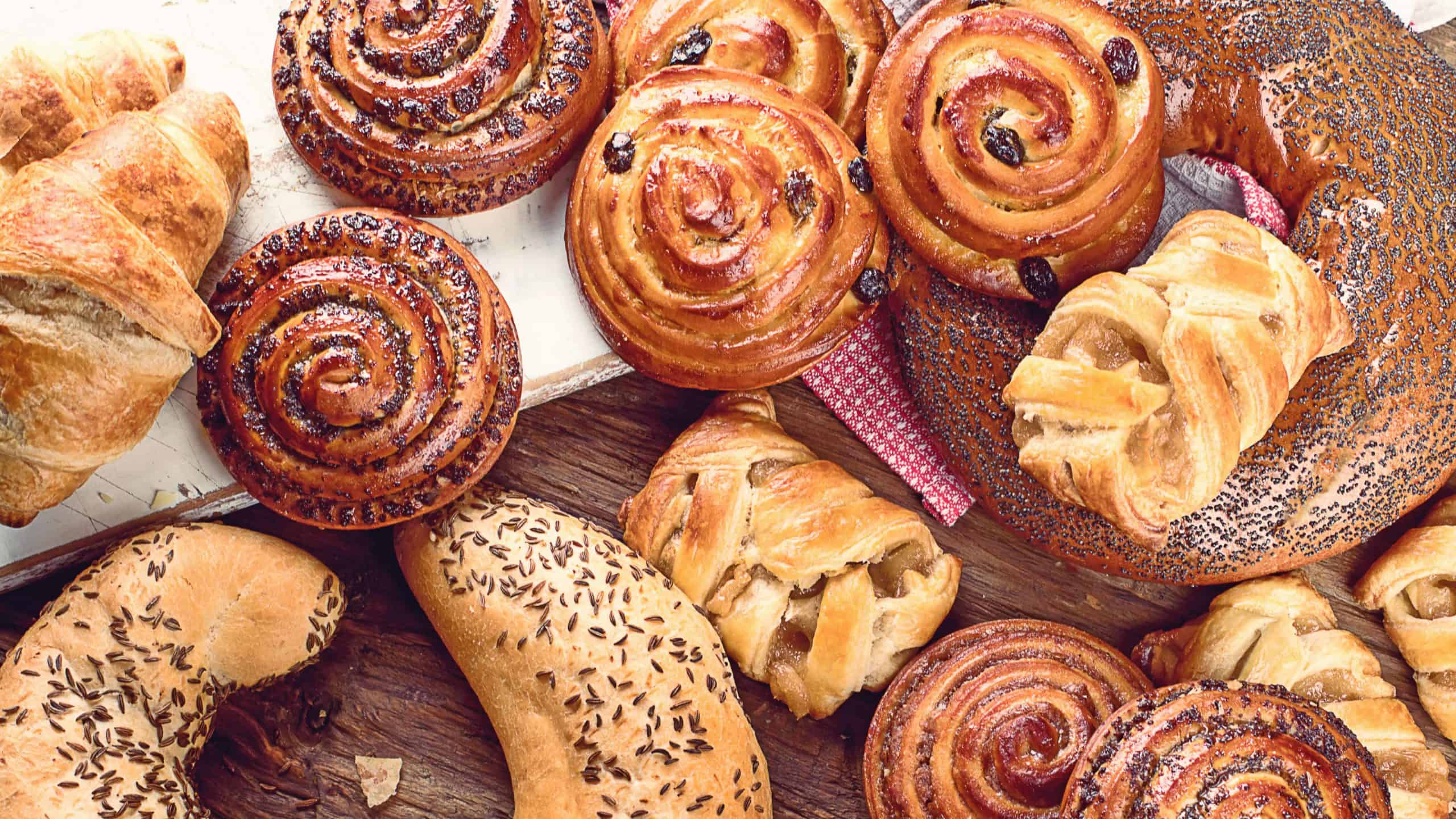 StockBreads, buns, croissants. Bakery ingredients on wooden background. Breakfast food concept. Top view