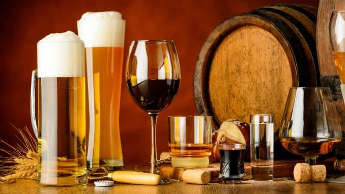 Bier- und Weingläser vor einem Barrique-Fass