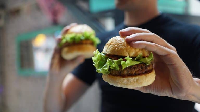hamburger in einer hand mit fingern