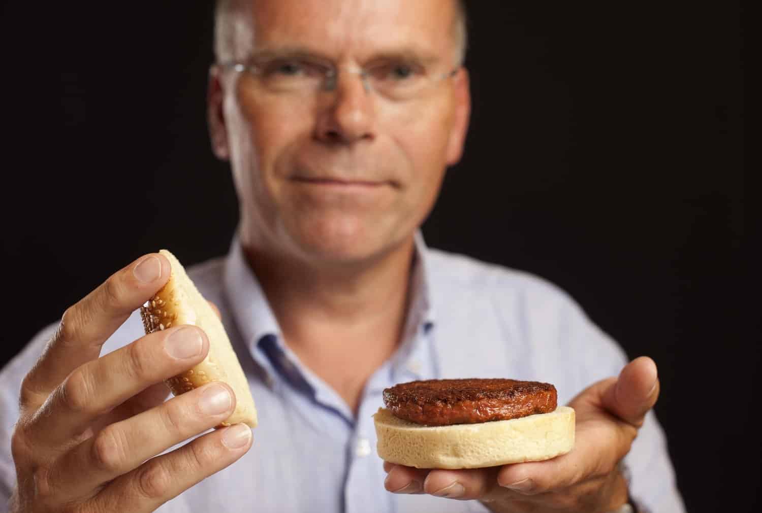 Meat, hält Hamburger aus kultiviertem Fleisch in die Kamera