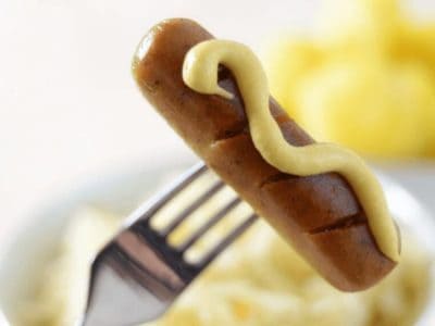 vegane Wurst mit Senf auf einer Gabel