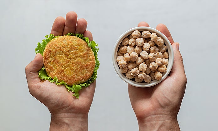 A person holding in one hand whole chickpeas and on the other a chickpea burger.