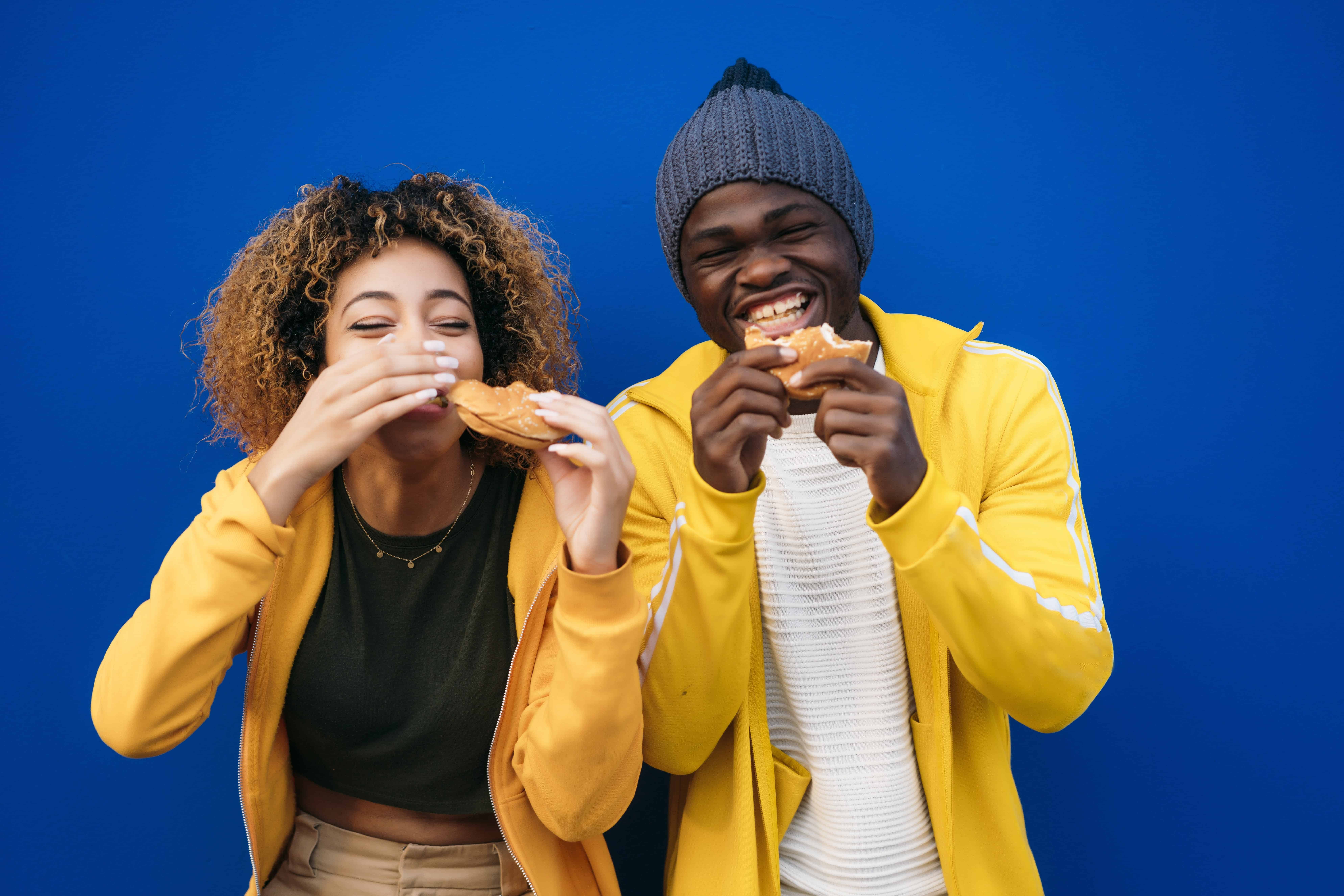 Young couple eating burger outdoors, APA