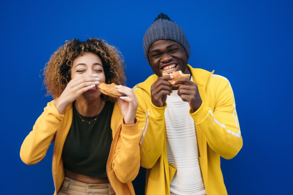 Young couple eating burger outdoors, APA